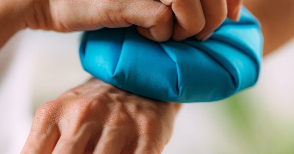 A close-up of a person pressing a bright blue ice pack against their wrist, possibly for pain relief. Managing inflammation with ice is a common part of recovery before starting the Best Tennis Elbow Exercises.