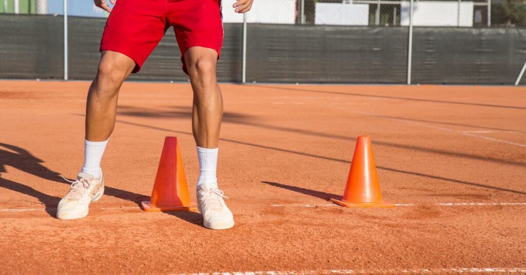 a man running in between orange cones for tennis warm up exercises on a tennis court