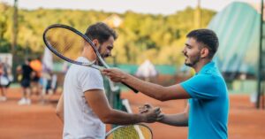 Two men tennis players giving each other a hand shake with their tennis rackets on their shoulders showing how famous rivalries congratulate each other