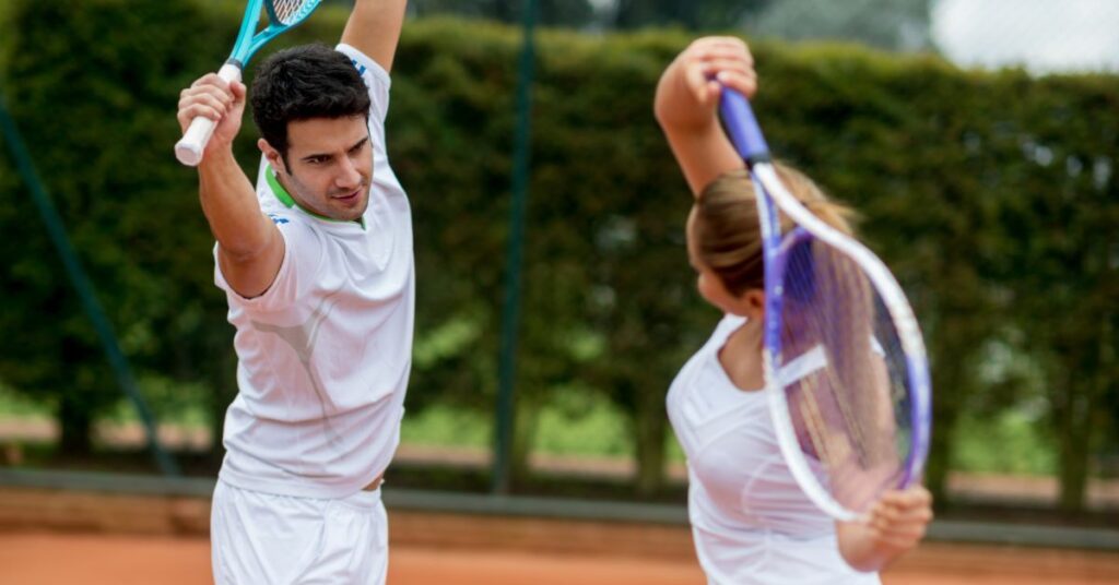 two tennis players performing tennis recovery stretches with tennis rackets over their heads