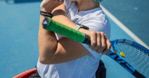 a person stretching a shoulder and arm while another arm is holding a tennis racket