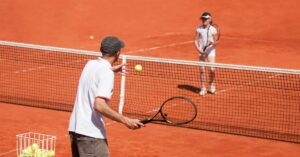 A tennis player coaching a younger tennis player to develop mental training for tennis
