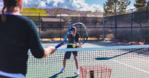Two players training on a tennis court applying what the tennis coach online taught them