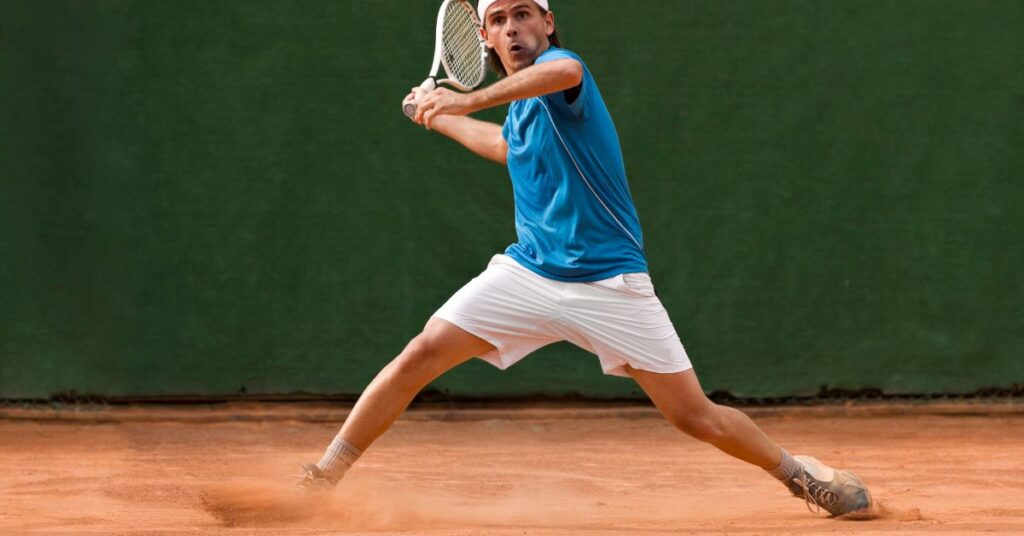 A tennis player in a stance about to hit a ball showing his flexible stance done by the doing the best agility exercises for tennis