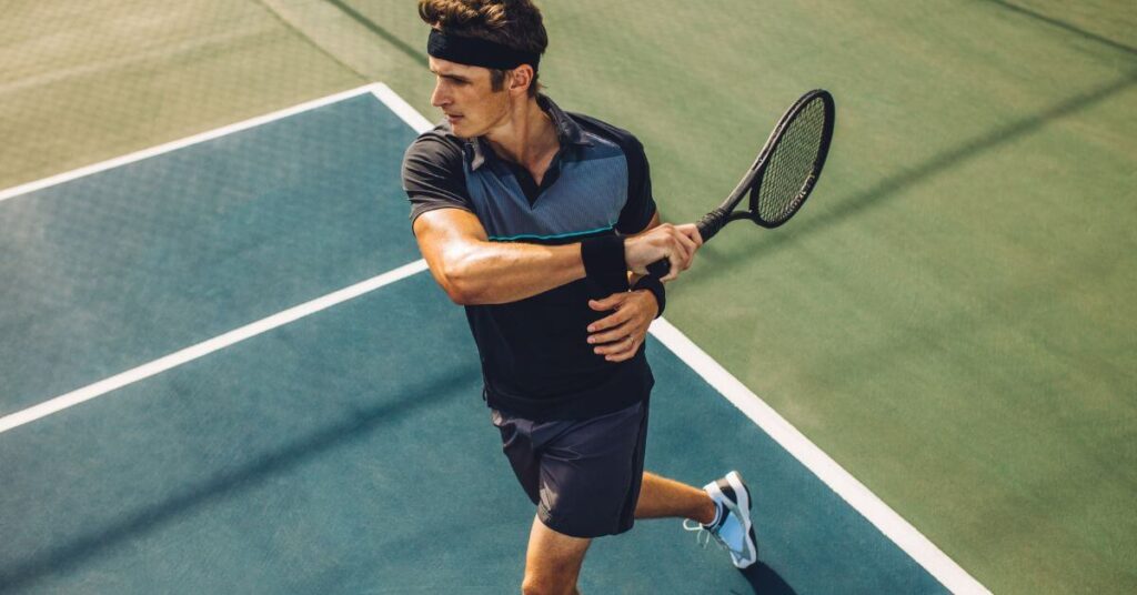 A tennis player looking physically fit in a hitting stance showing the health benefits of tennis