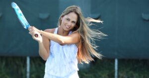 Gaby Paz swinging a tennis racket with a smile for tennis facts