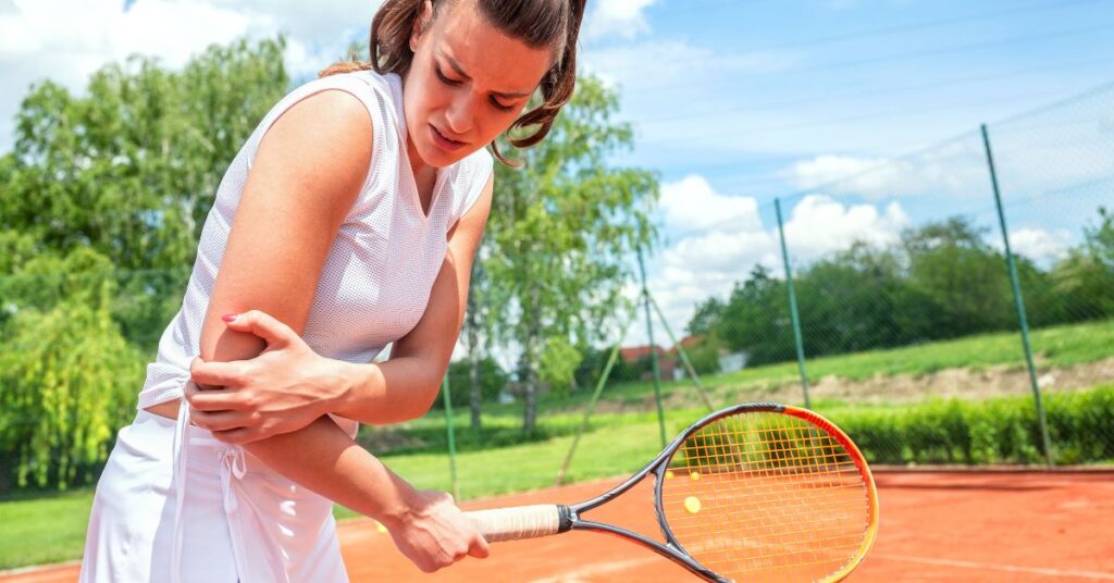 A tennis player holding her arm because of one of the tennis common injuries