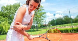 A tennis player holding her arm because of one of the tennis common injuries